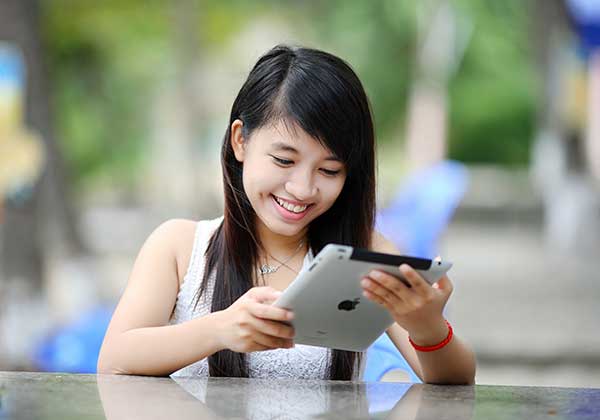 Image of a girl smiling at her Ipad